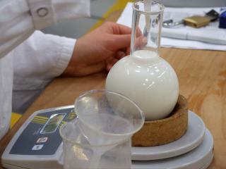 Milch im Rundkolben, auf einer Waage im Labor.