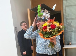 Christina Hartwig nach ihrer erfolgreichen Promotion mit Hut und Blumenstrauß.