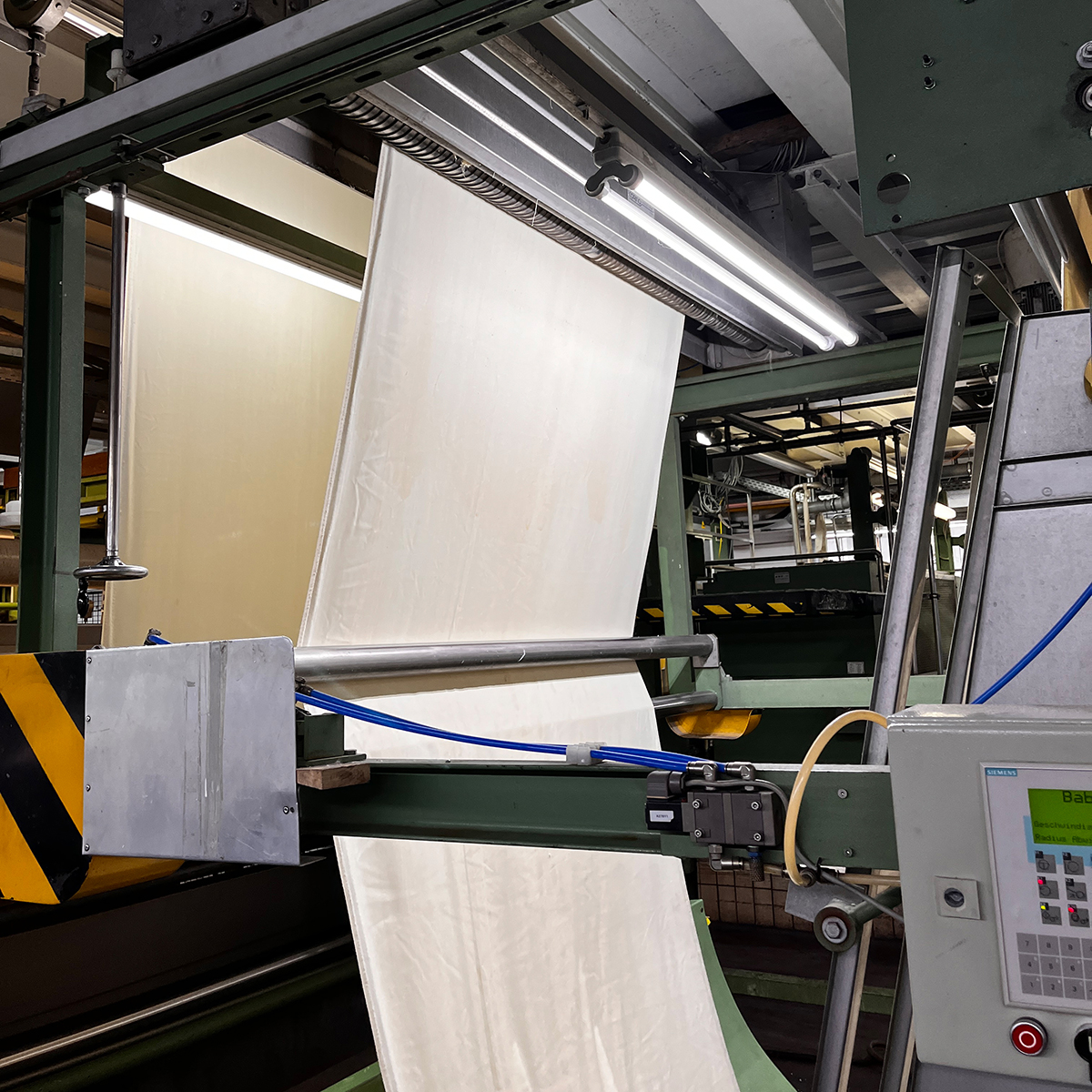 Coating large lengths of fabric in a factory
