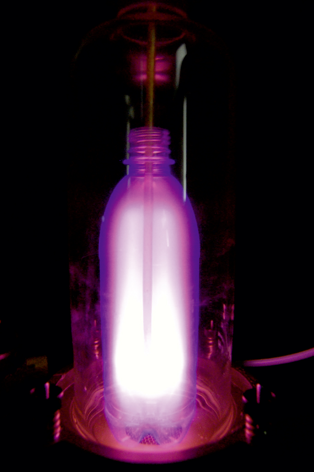 Coating the inside of the bottle using low-pressure plasma (bright pink).