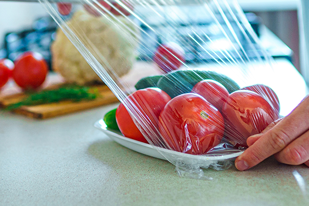 Packing foil covering bowl with fresh tomatoes and cucumbers
